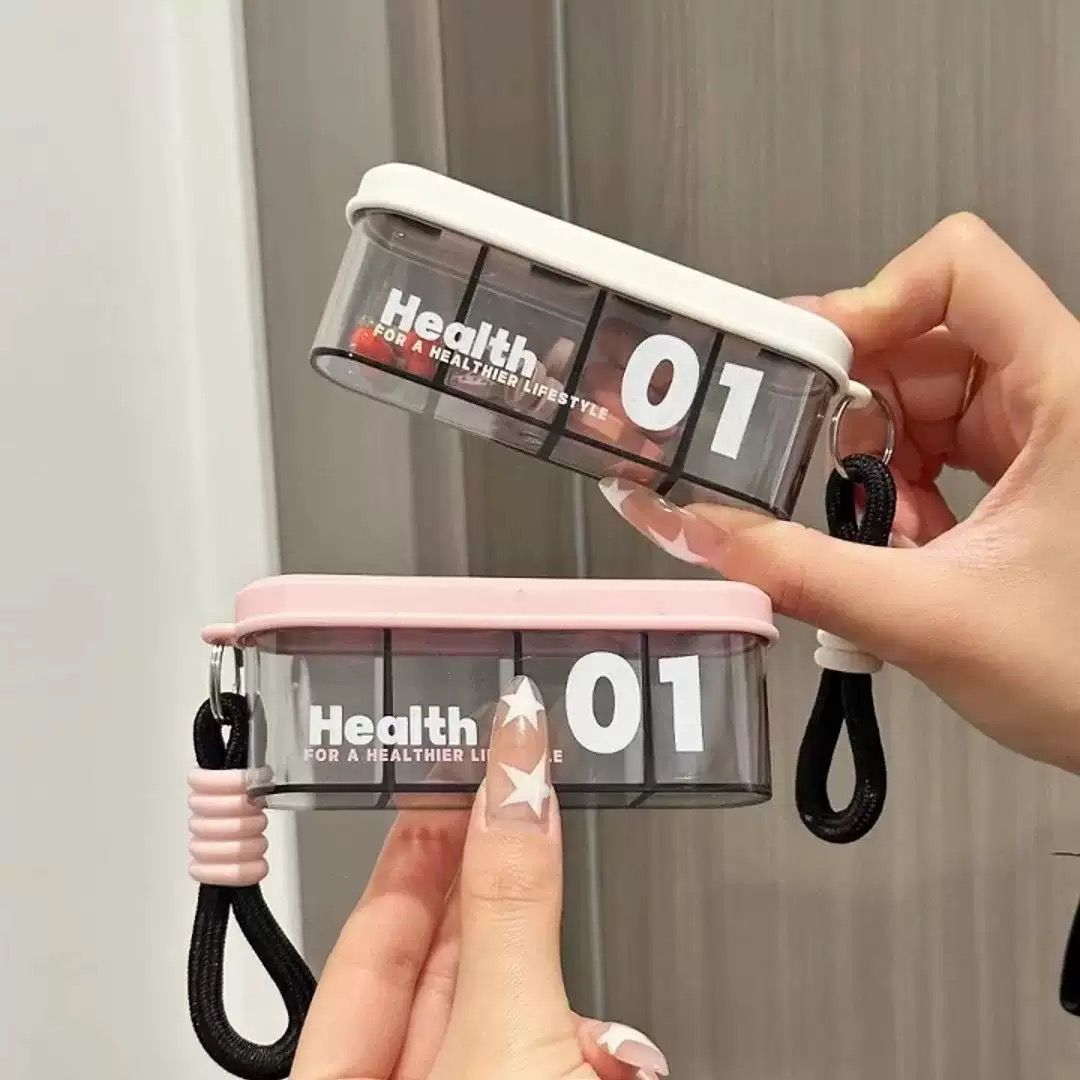 Portable travel pill organizer with four compartments and a carrying strap.